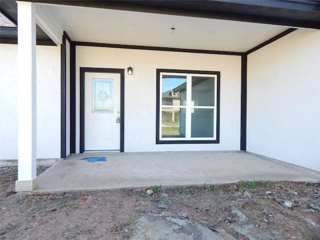 entrance to property featuring a patio area and stucco siding