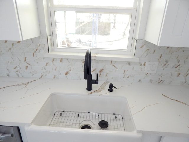 interior details with white cabinets, a sink, and backsplash