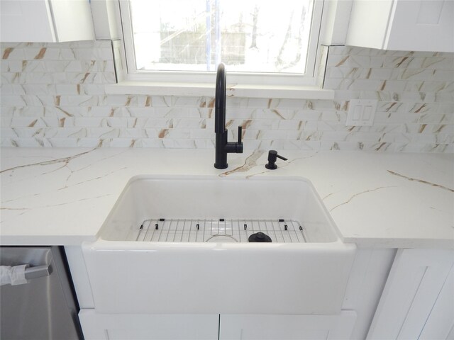 interior details with light stone counters, a sink, white cabinetry, and decorative backsplash