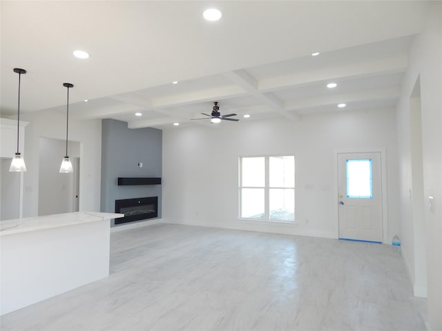 unfurnished living room with beam ceiling, recessed lighting, a glass covered fireplace, coffered ceiling, and baseboards