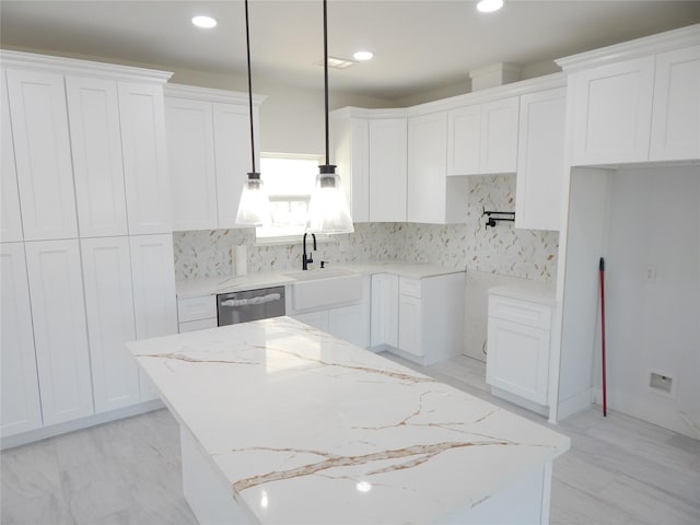 kitchen featuring a kitchen island, decorative light fixtures, a sink, white cabinetry, and stainless steel dishwasher