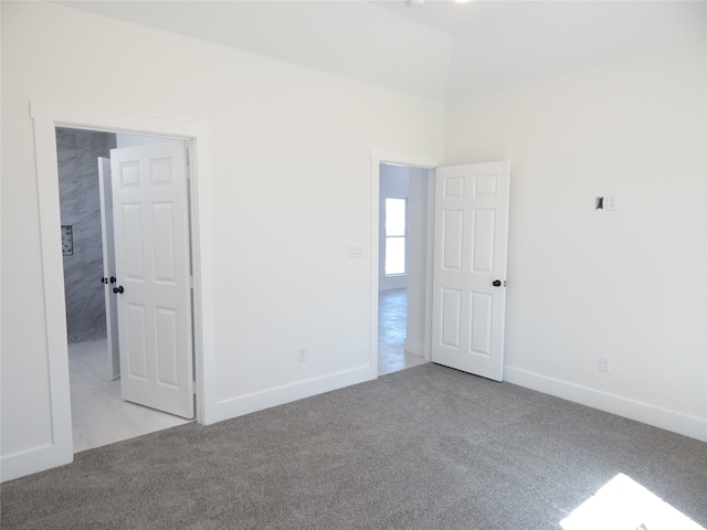 spare room featuring light carpet, baseboards, and lofted ceiling