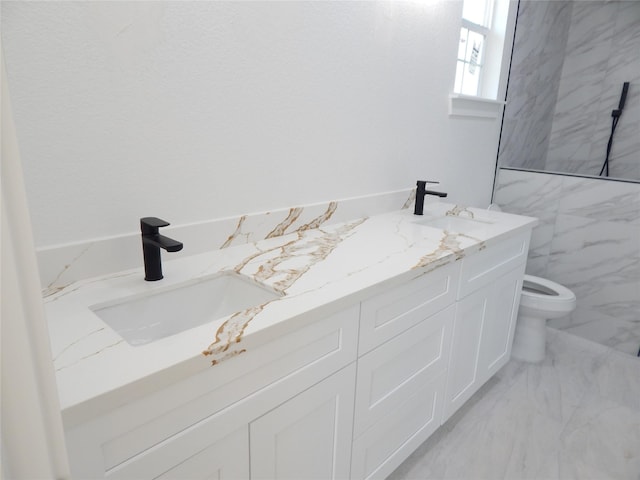 full bathroom with marble finish floor, double vanity, a sink, and toilet