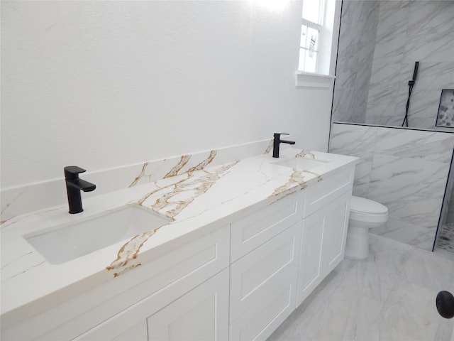 bathroom featuring double vanity, marble finish floor, toilet, and a sink