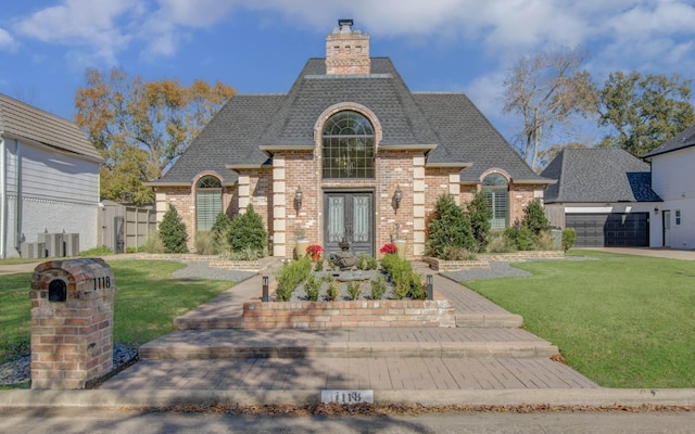 french country home featuring a garage and a front lawn