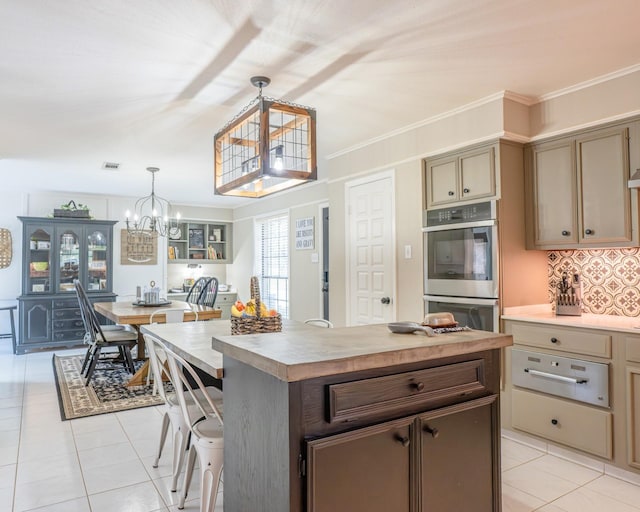 kitchen with crown molding, double oven, hanging light fixtures, a kitchen island, and a chandelier