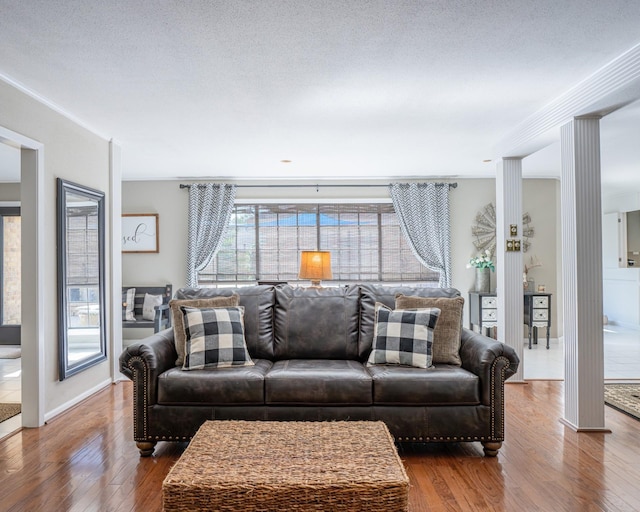 living room featuring decorative columns, hardwood / wood-style floors, and a textured ceiling