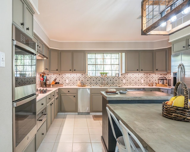 kitchen with crown molding, sink, light tile patterned floors, decorative backsplash, and stainless steel appliances