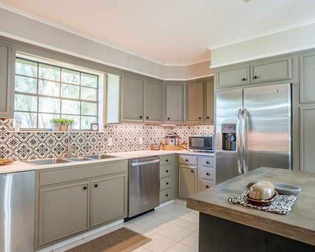 kitchen with crown molding, sink, tasteful backsplash, light tile patterned floors, and stainless steel appliances