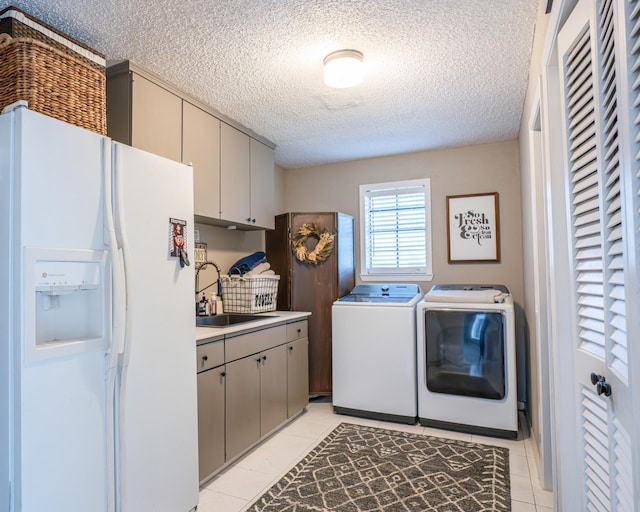 washroom featuring sink, independent washer and dryer, light tile patterned floors, cabinets, and a textured ceiling