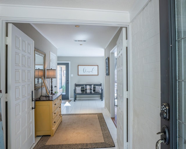 hallway featuring crown molding and light tile patterned floors