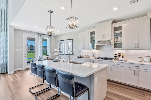 kitchen featuring pendant lighting, extractor fan, white cabinetry, sink, and a breakfast bar area