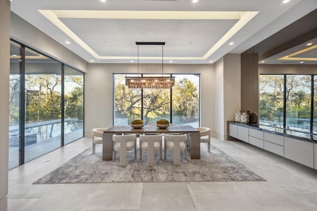 dining area featuring a chandelier, plenty of natural light, and a tray ceiling