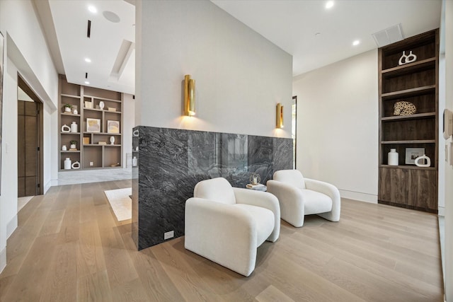 sitting room featuring light wood-type flooring and built in shelves