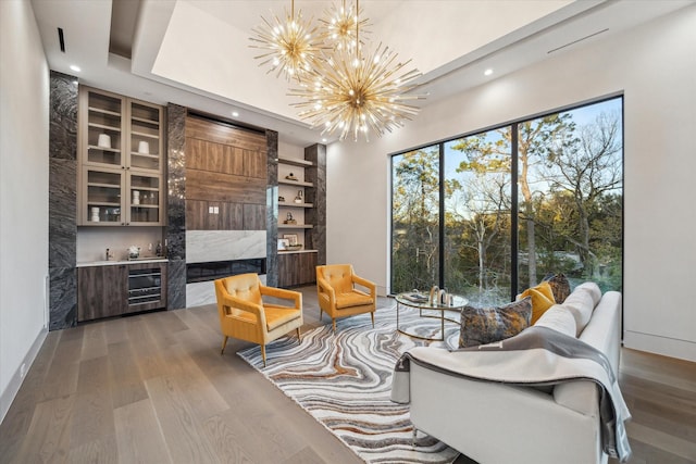 living area featuring beverage cooler, wood-type flooring, built in features, a notable chandelier, and bar area