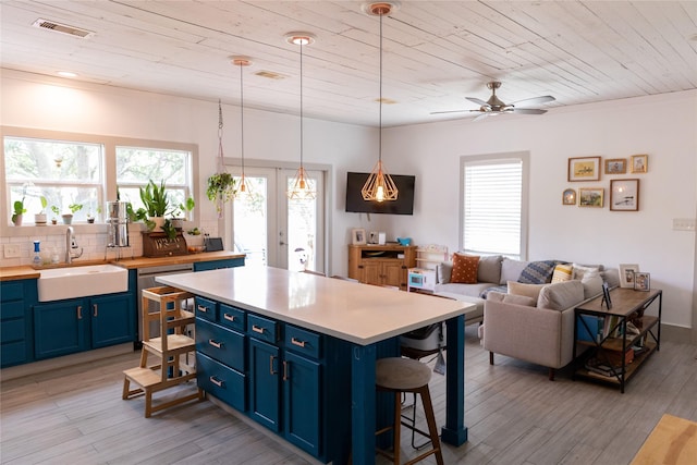 kitchen featuring blue cabinets, sink, wooden ceiling, a kitchen breakfast bar, and pendant lighting