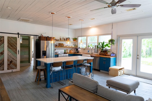 living room featuring sink, ceiling fan, light hardwood / wood-style floors, a barn door, and wooden ceiling