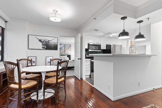 dining room featuring sink, crown molding, and dark hardwood / wood-style floors