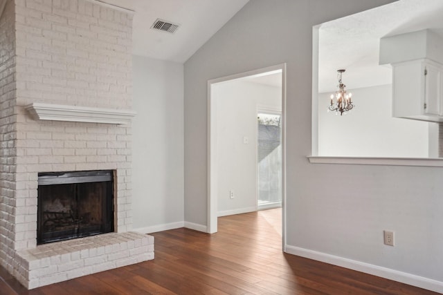 unfurnished living room with a brick fireplace, an inviting chandelier, dark wood-type flooring, and lofted ceiling