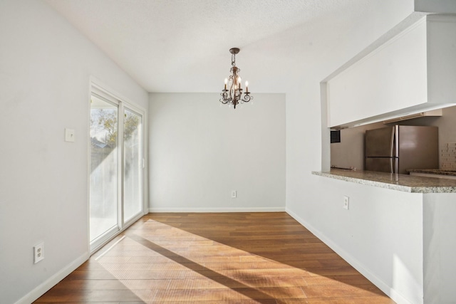 unfurnished dining area featuring wood-type flooring and an inviting chandelier