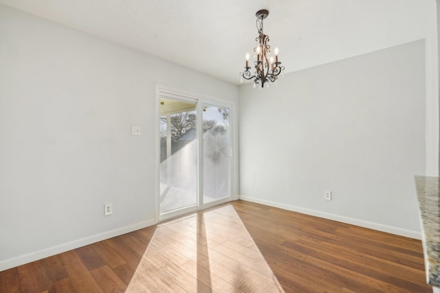 empty room featuring hardwood / wood-style flooring and an inviting chandelier