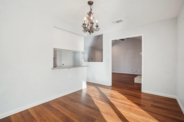 empty room featuring an inviting chandelier and dark hardwood / wood-style flooring