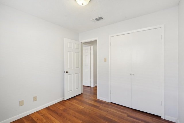 unfurnished bedroom with dark wood-type flooring and a closet