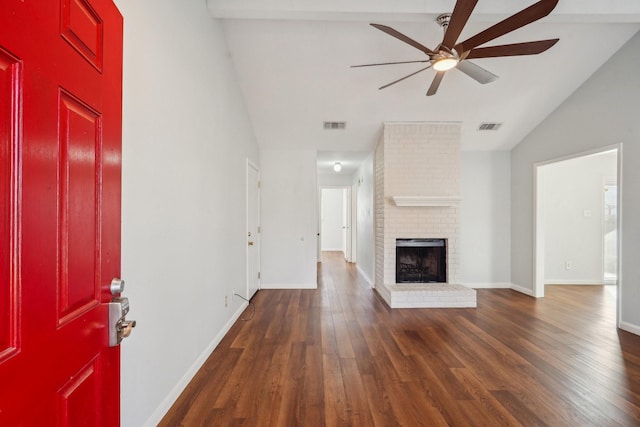 unfurnished living room featuring ceiling fan, dark wood-type flooring, vaulted ceiling, and a brick fireplace