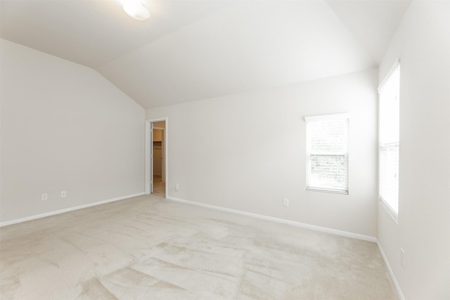 empty room featuring plenty of natural light, light carpet, and vaulted ceiling