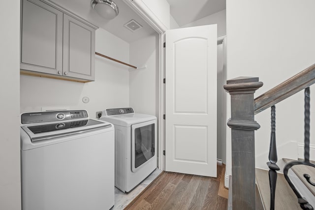 clothes washing area featuring cabinets, separate washer and dryer, and dark hardwood / wood-style flooring