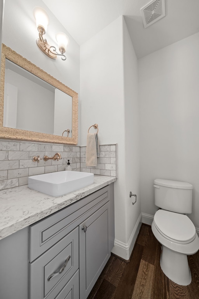 bathroom with tasteful backsplash, vanity, toilet, and wood-type flooring