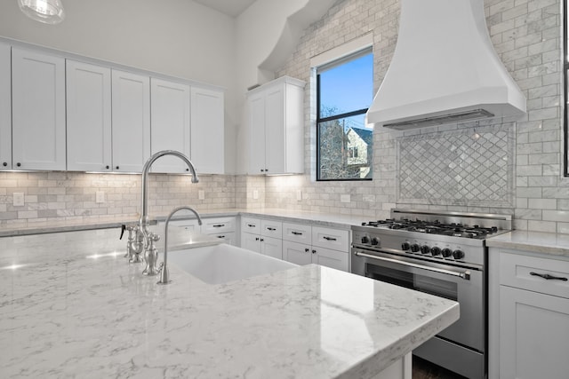 kitchen featuring decorative backsplash, stainless steel range, custom exhaust hood, and white cabinets