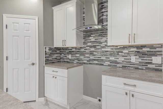 kitchen featuring white cabinetry, wall chimney range hood, and decorative backsplash