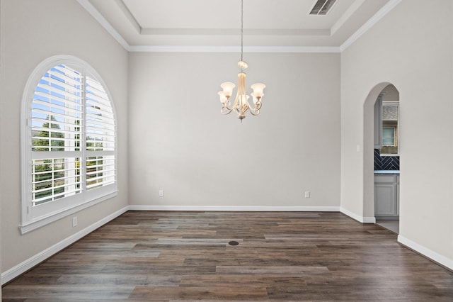 empty room featuring a tray ceiling, dark hardwood / wood-style floors, and a notable chandelier