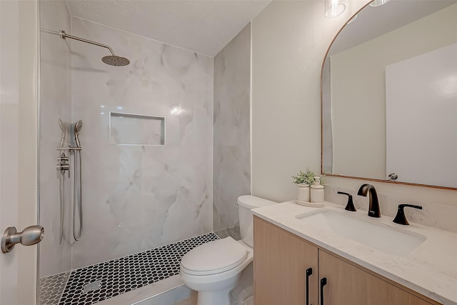 bathroom featuring toilet, vanity, and a tile shower