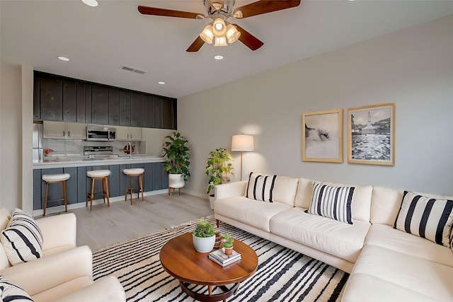 living room featuring ceiling fan and light hardwood / wood-style flooring