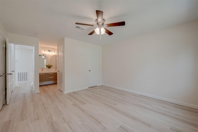 unfurnished bedroom featuring ceiling fan, connected bathroom, a closet, and light wood-type flooring