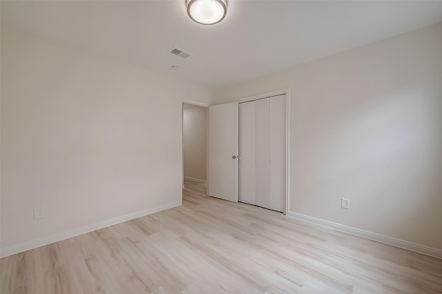 unfurnished bedroom with light wood-type flooring and a closet