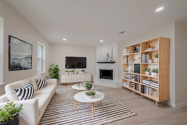 living room with light hardwood / wood-style flooring and a brick fireplace