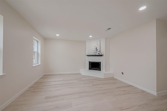 unfurnished living room featuring a fireplace and light hardwood / wood-style floors