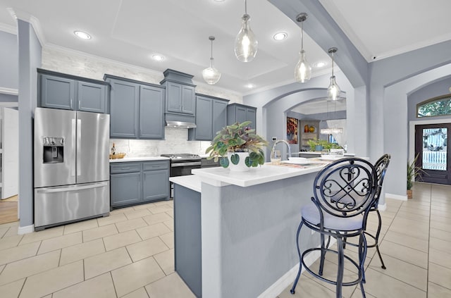 kitchen featuring pendant lighting, a kitchen breakfast bar, decorative backsplash, ornamental molding, and stainless steel appliances