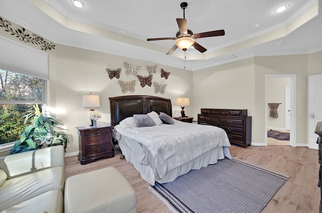 bedroom with a raised ceiling, ornamental molding, ceiling fan, and light wood-type flooring