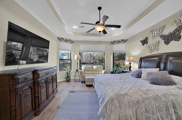 bedroom with crown molding, ceiling fan, a tray ceiling, and light hardwood / wood-style floors