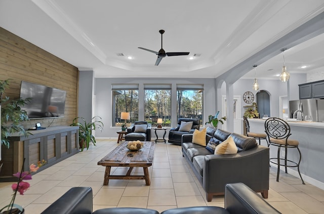 tiled living room featuring ornamental molding, a raised ceiling, and ceiling fan