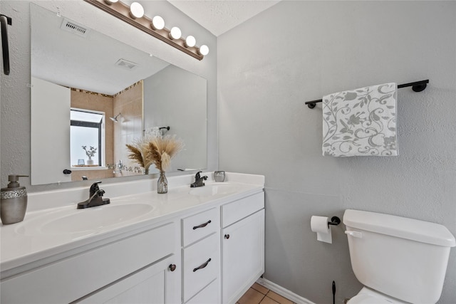 bathroom with vanity, toilet, tile patterned floors, and a textured ceiling