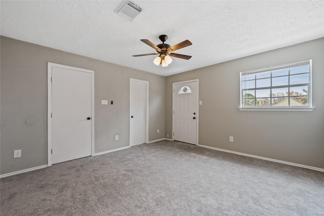 empty room with ceiling fan, a textured ceiling, and carpet flooring