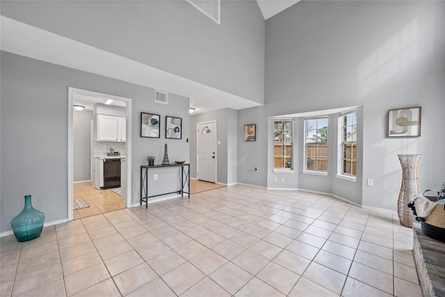 unfurnished living room with a towering ceiling and light tile patterned flooring