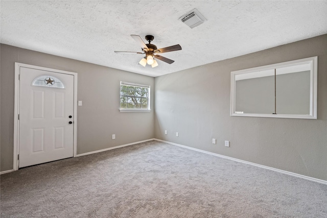 carpeted spare room featuring ceiling fan and a textured ceiling