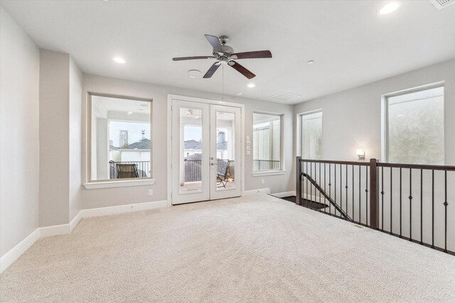 spare room with french doors, ceiling fan, and light carpet