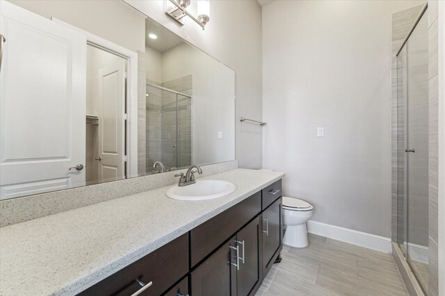 bathroom with vanity, toilet, and a shower with shower door